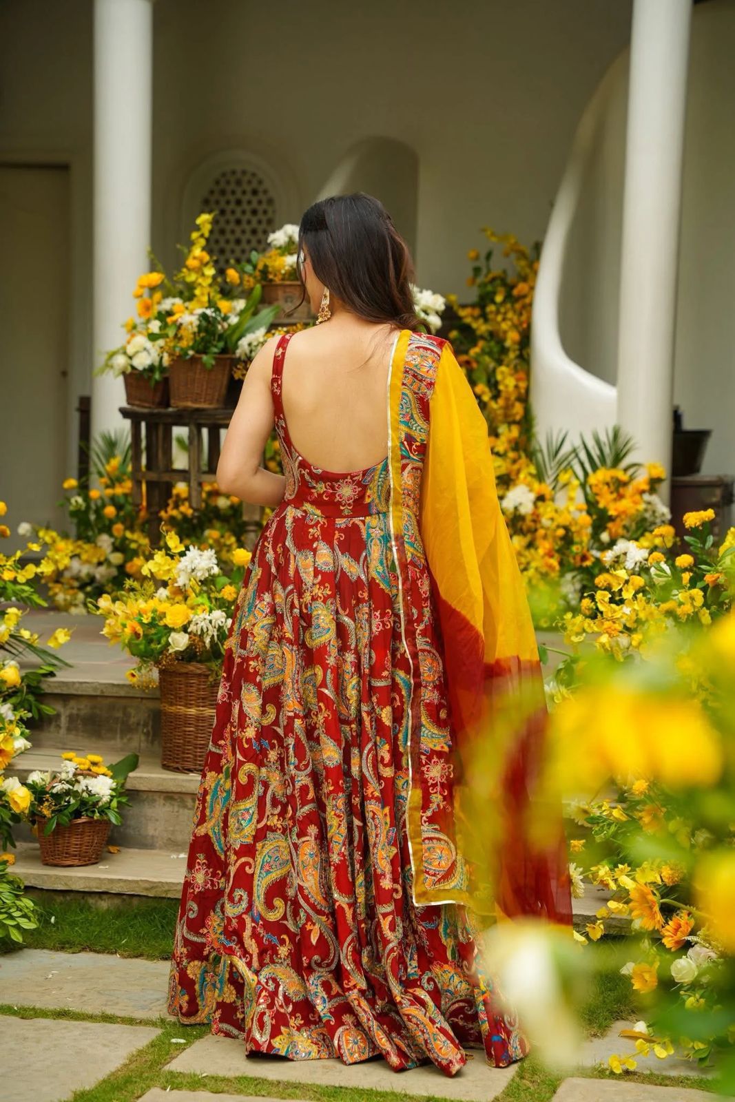 Back view of red printed Anarkali gown with flowing yellow organza dupatta