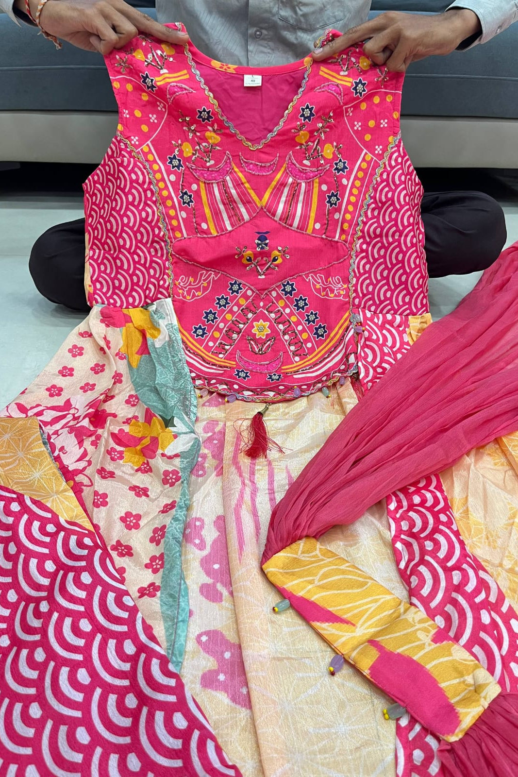 Detailed view of hand work on the pink Chinon suit yoke with traditional decorative motifs
