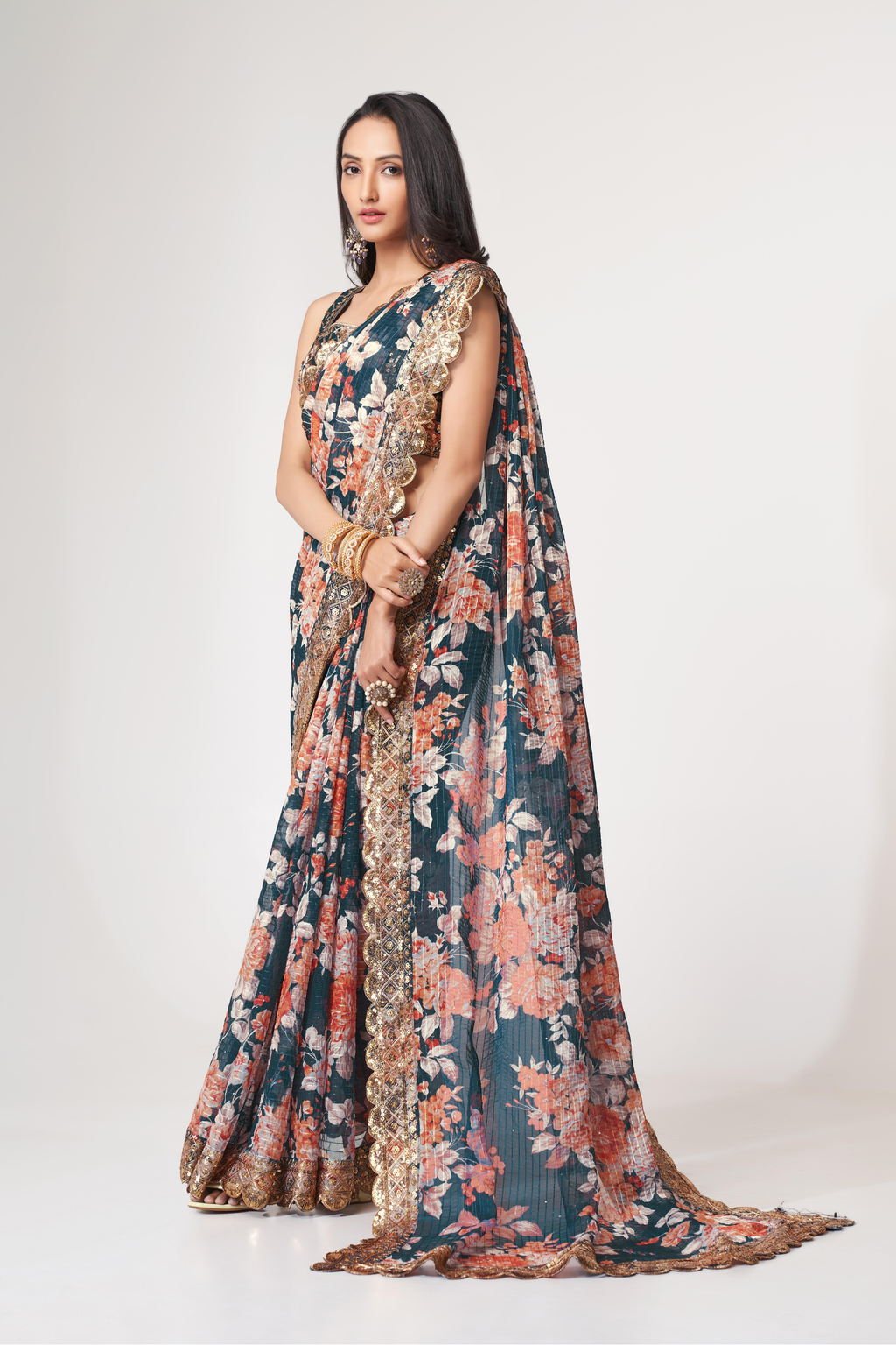 Deep teal floral organza saree shown from the back with gold sequin blouse embroidery and ornate border
