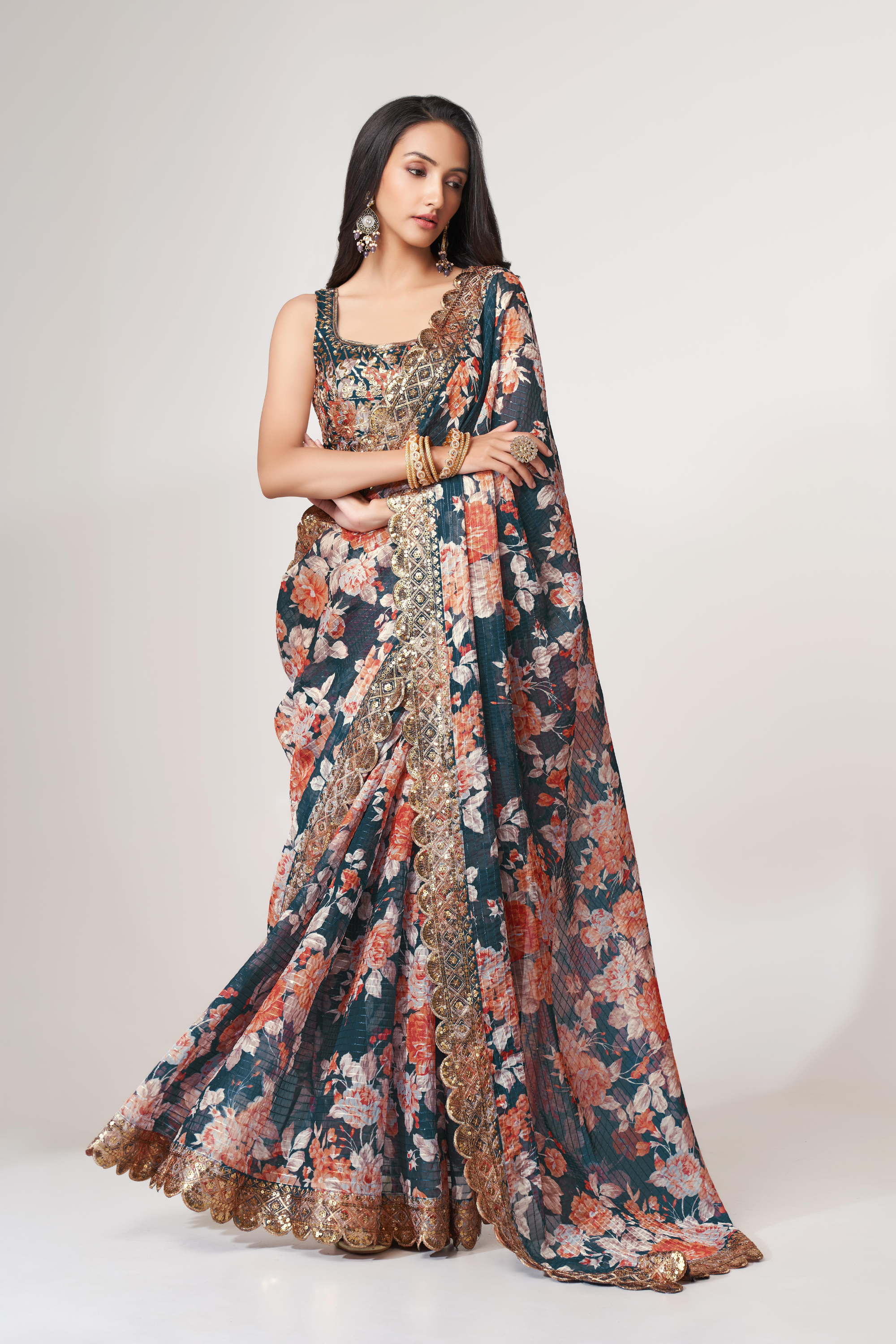 Front drape of a deep teal floral organza saree with sequined blouse, peach florals and gold detailing