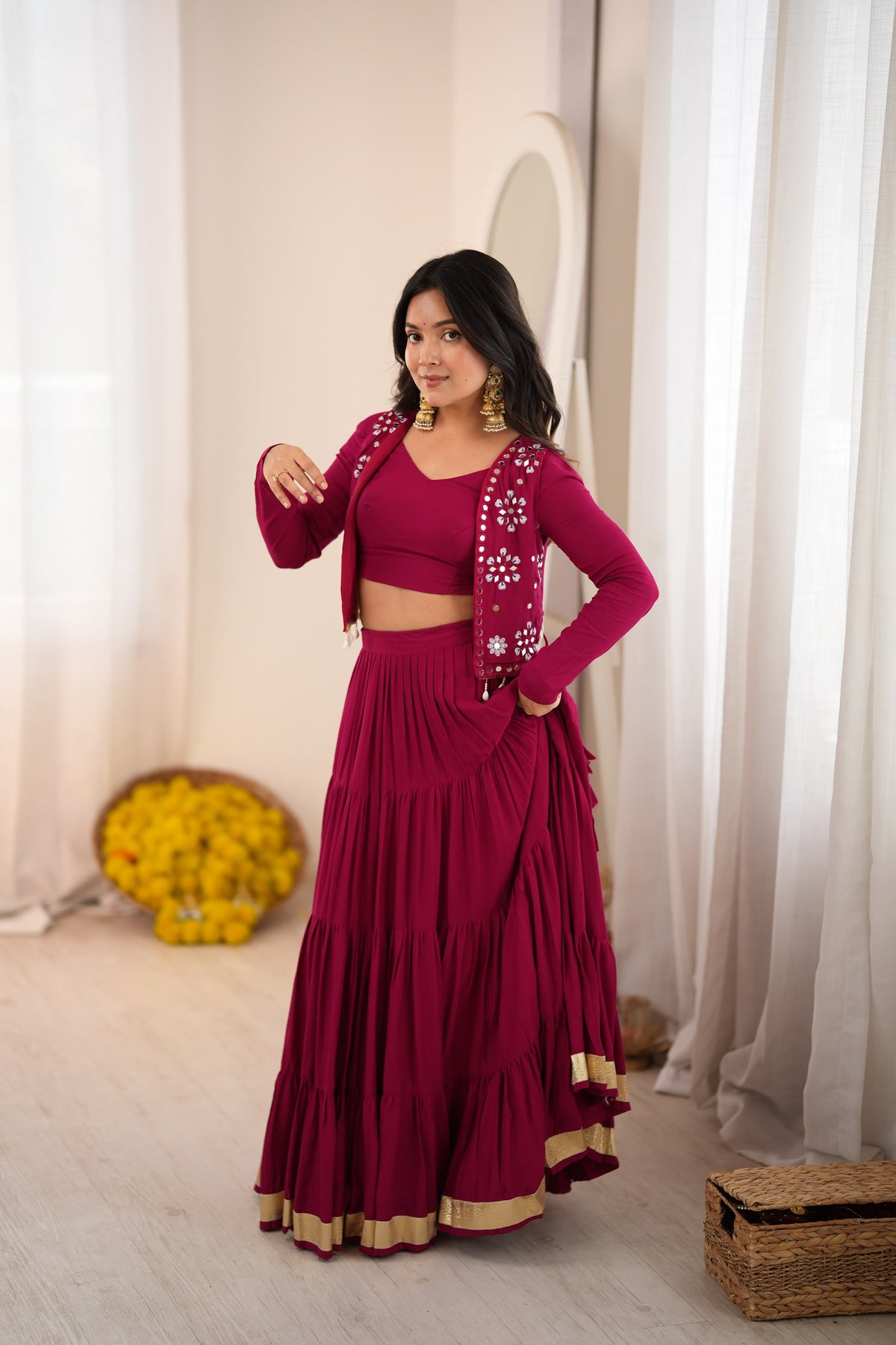 Magenta Indian lehenga choli in a side pose showing its tiered skirt and gold hem