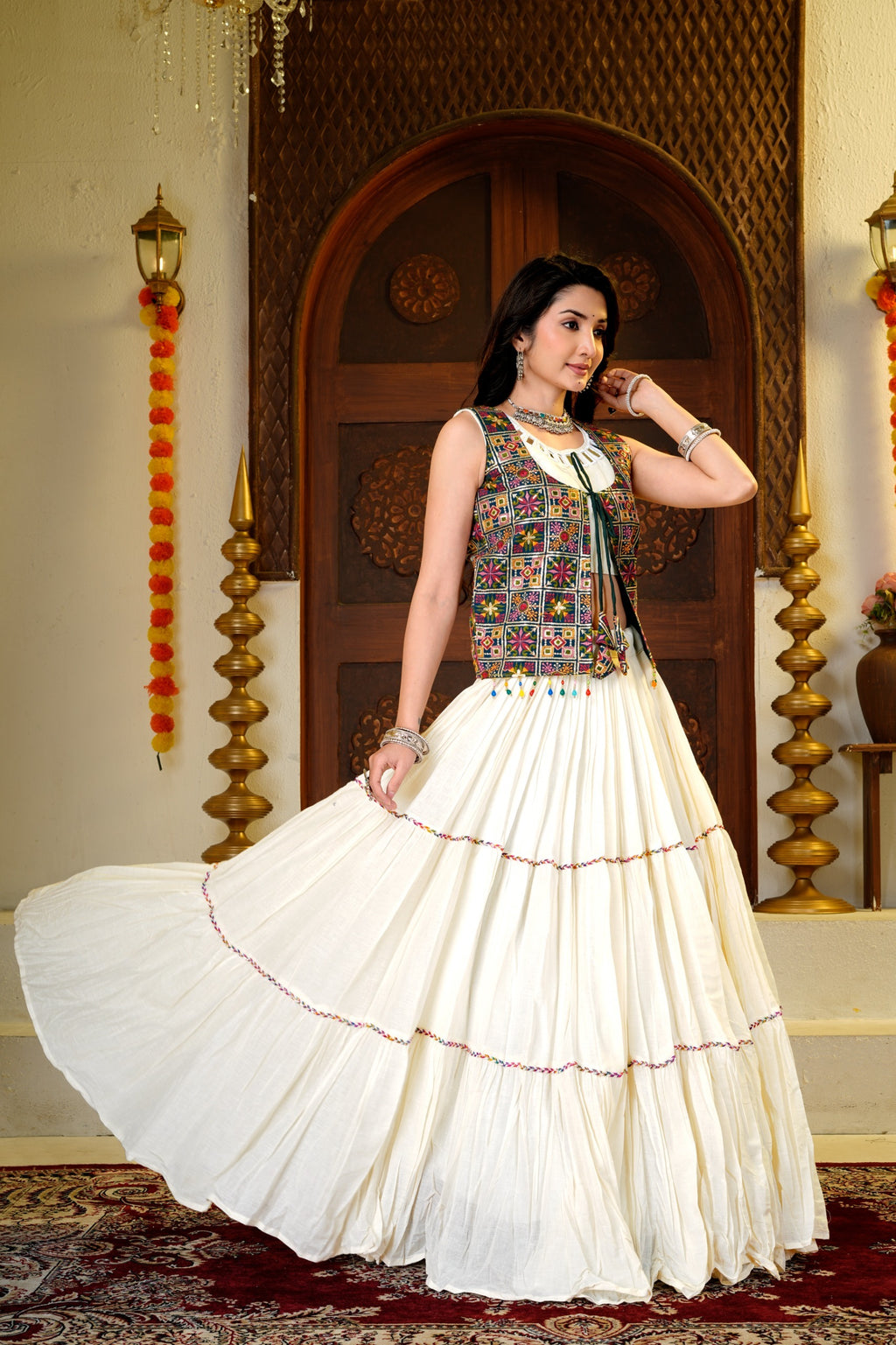 Side pose showing the flowing Indian lehenga choli skirt, mirror-work choli and embroidered shrug
