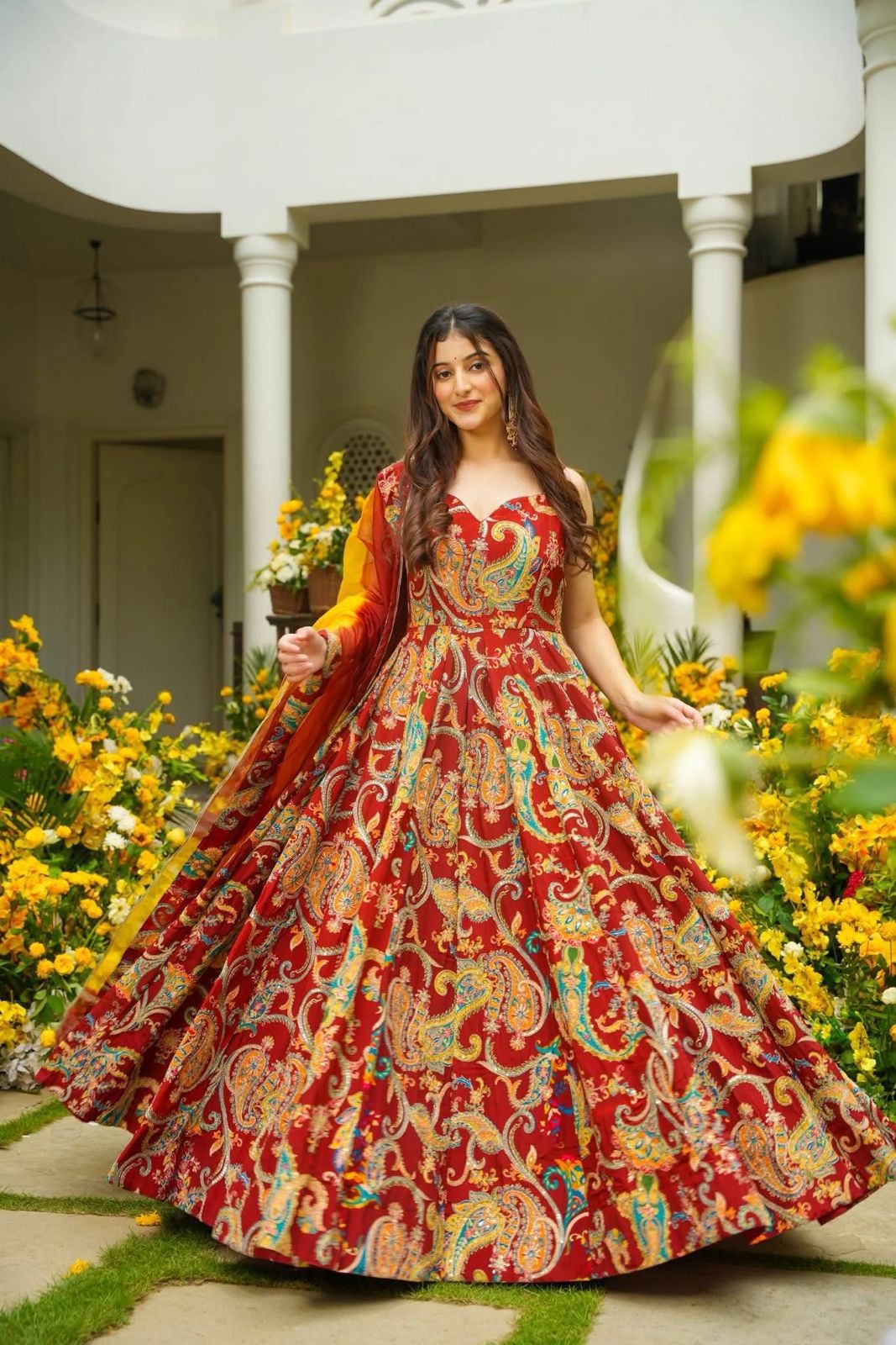 Full-flair view of a red printed Anarkali gown with contrasting yellow dupatta