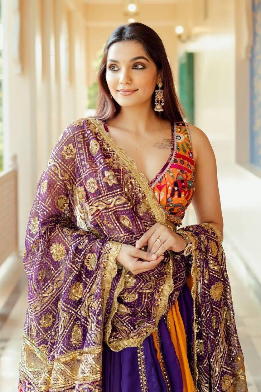 Purple mirror work dupatta draped over a multicolor Navratri chaniya choli with orange accents