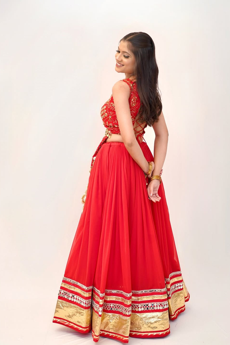 Side silhouette of red Indian lehenga choli with a wide flowing skirt and embellished hem
