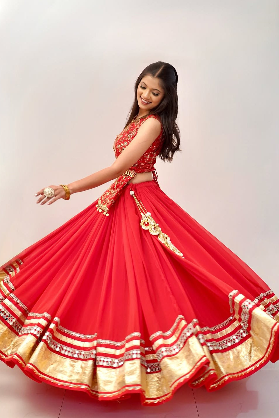 Side view of red Indian lehenga choli with flowing skirt and embellished border