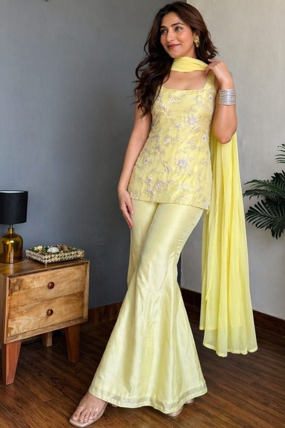 Woman wearing a yellow georgette suit set with embroidered top, palazzo and dupatta
